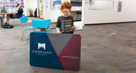 girl with large Chandler Public Library card