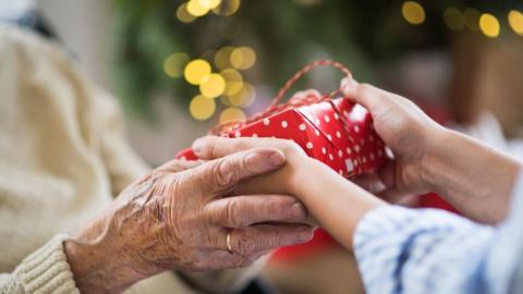 Close-up of hands of senior and young woman holding a present at Christmas