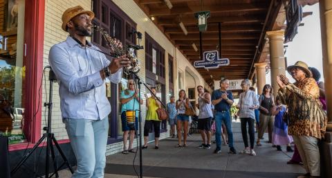 Man playing alto saxophone in front of a crowd of people in Downtown Chandler