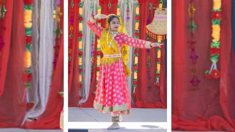Woman in a traditional Indian dress dancing on a stage surrounded by red and gold drapery and decor