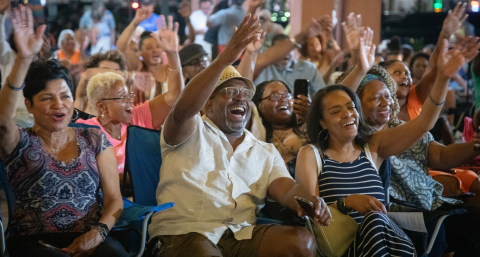 Group of people sitting and raising arms in celebration