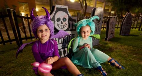Child in purple Halloween costume sitting next to a child in a light blue Halloween costume