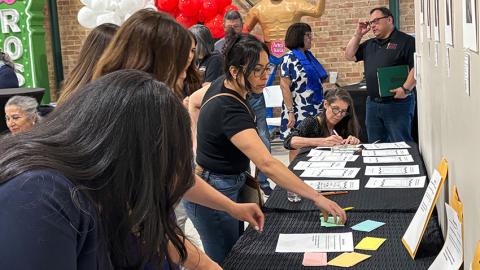 Women grabbing pieces of paper off a table
