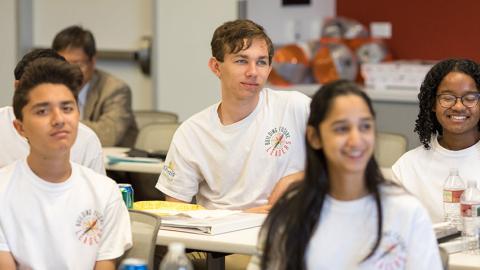 Four teenagers sitting at a table in white shirts