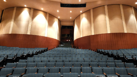 Theater with blue upholstered seats in front of large, round columns