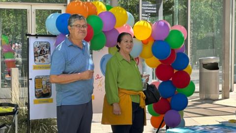 Seniors attending Golden Neighbors celebration; standing in front of a colorful balloon arch