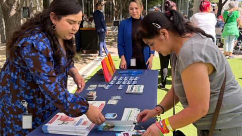 Female Golden Neighbor reviews brochures from a city department at an informational booth
