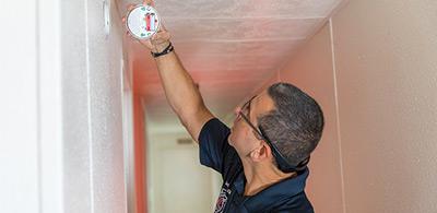 photo showing someone installing a smoke alarm in a house