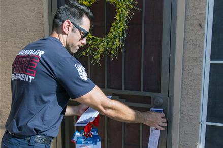 Chandler Firefighter placing a door hanger for water safety