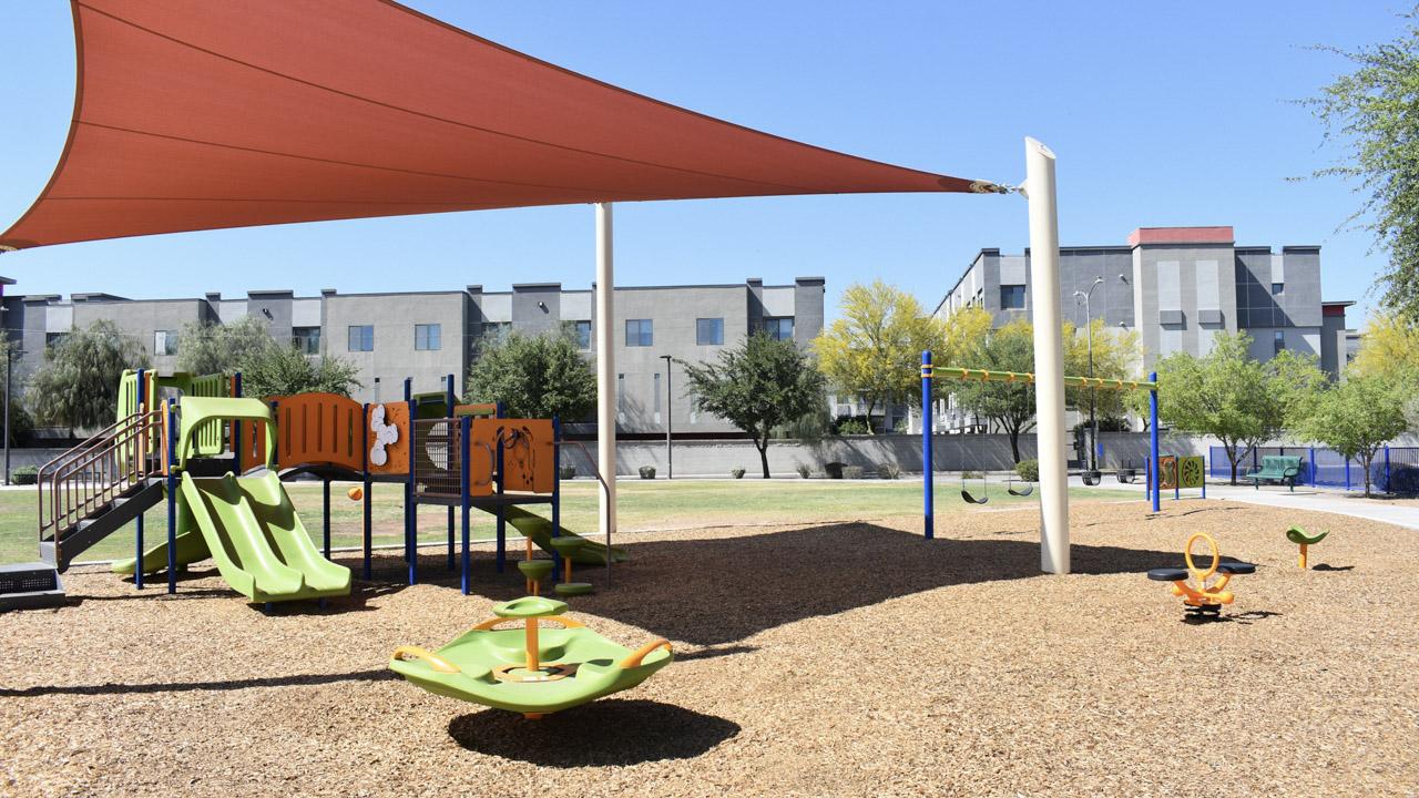 Playground with swing sets, spinner, and play structure at Harris Park