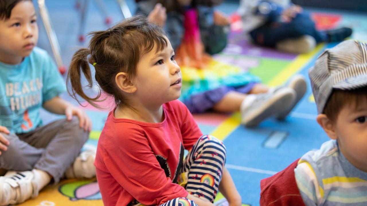 young girl listens to teacher in building blocks program