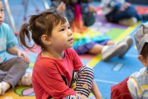 young girl listens to teacher in building blocks program