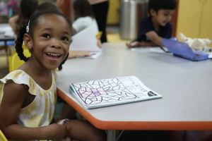 young girl smiling while coloring