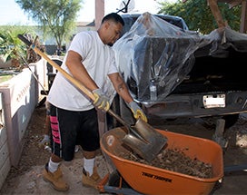 A resident shoveling dirt into a wheelbarrow A resident shoveling dirt into a wheelbarrow